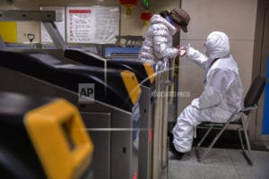 A-worker-wearing-a-hazardous-materials-suit-gives-directions-to-a-passenger-at-a-subway-station-in-Beijing